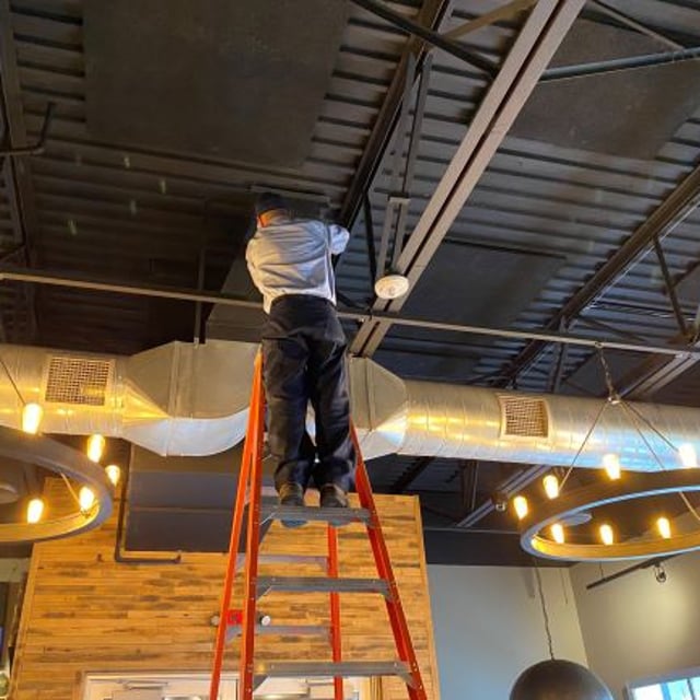 Aire Serv Technician working on installing ductwork inside building