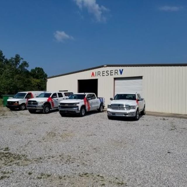 Four Aire Serv vehicles located outside of Aire Serv warehouse building.