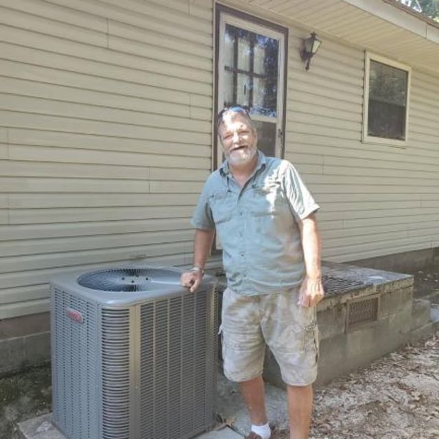 Customer leaning against new Lennox heat pump installed outside of home.