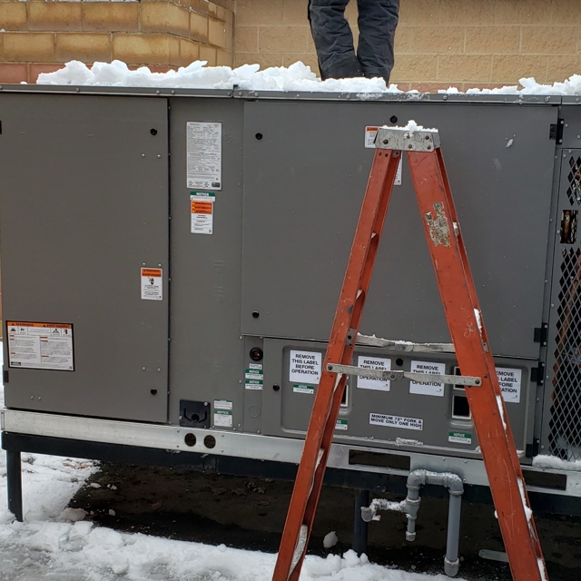 Tech on HVAC Unit in the snow