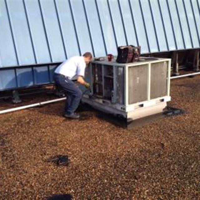 Aire Serv technician replacing rooftop package units.