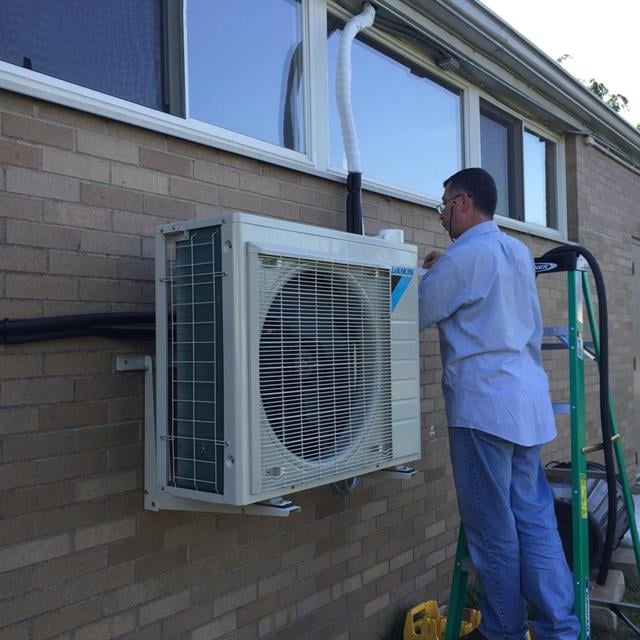 A technician putting the finishing touches on an outdoor HVAC installation.