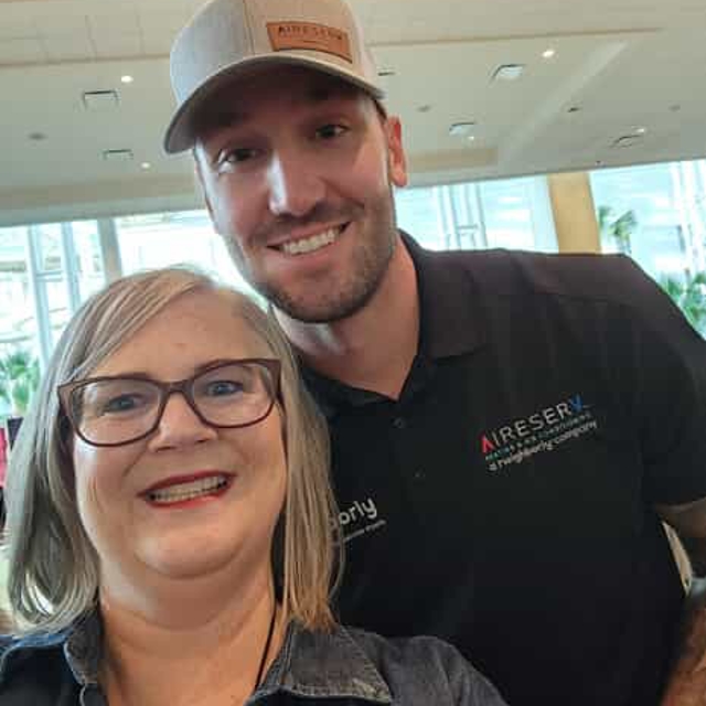 two people smiling with aire serv shirts