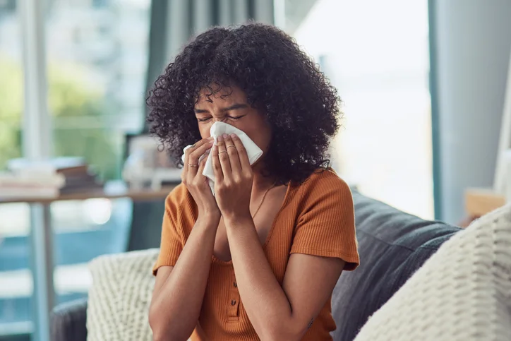 Shot of a young woman blowing her nose with a tissue at home | Aire Serv of Birmingham