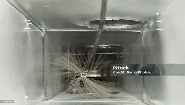 A close-up view of the inside of an air duct where a rotating brush tool is being used to clean it. | Aire Serv of North Central Arizona