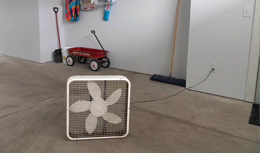 Box fan in middle of a mostly empty garage