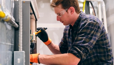 A repairman working inside a home, repairing a furnace | Aire Serv of Birminham