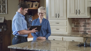 Air conditioning repairman speaking with a customer in their home.