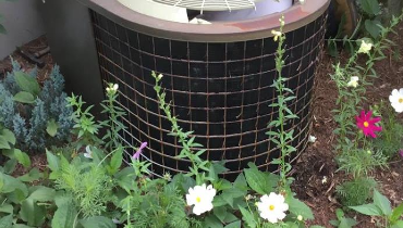 air conditioning unit outside surrounded by plants