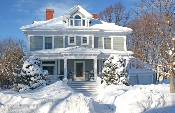 Large, older residential home covered with a lot snow