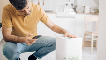 A man sets up an air purifier with an app on his mobile phone.