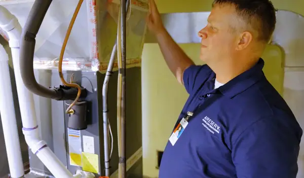 Aire serv technician inspecting a HVAC unit.