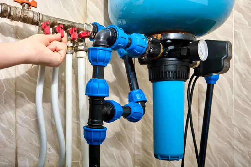 A technician installs a whole house water filter after a pressure tank.