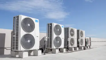 A set of air conditioning units installed on the roof of a commercial building with a blue sky in the background. | Aire Serv of North Central Arizona