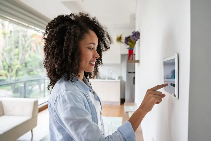 A woman uses a smart home control panel mounted on the wall. | Aire Serv of Citrus County