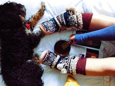 Woman relaxing on bed with dog.