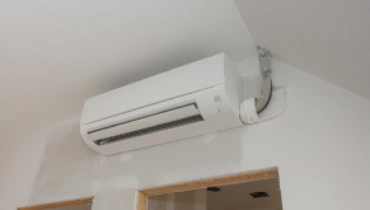 A white ductless mini split air conditioner at the top of a white wall.