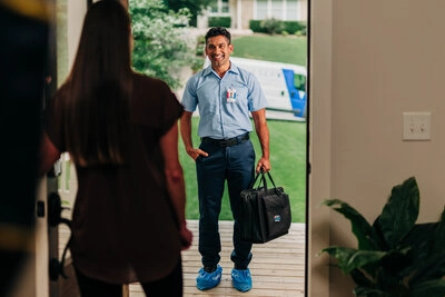 An Aire Serv emergency HVAC tech happily greeting a customer at their front door