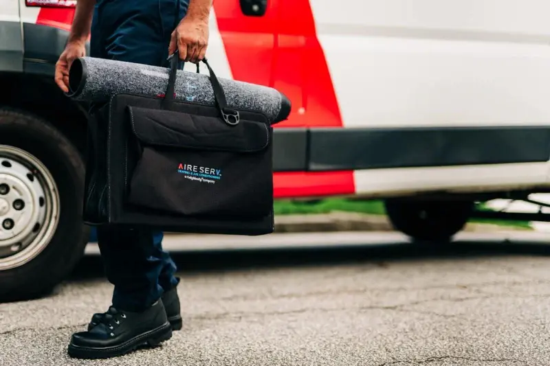 Close-up of Aire Serv technician carrying branded tool bag.