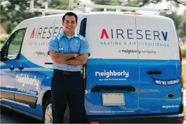 Male Aire Serv technician standing with arms crossed beside branded van.