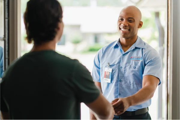 Smiling male Aire Serv technician arriving for residential service appointment.