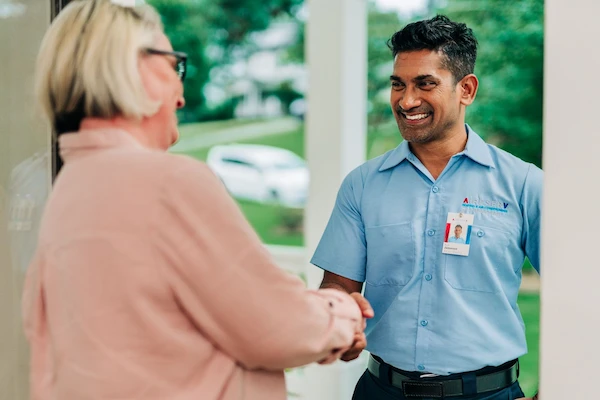 Aire Serv service professional greeting homeowner in entryway.