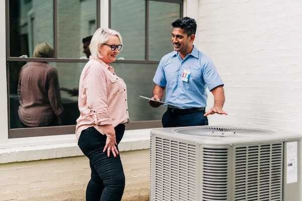 Aire Serv service professional reviewing HVAC service options with homeowner.