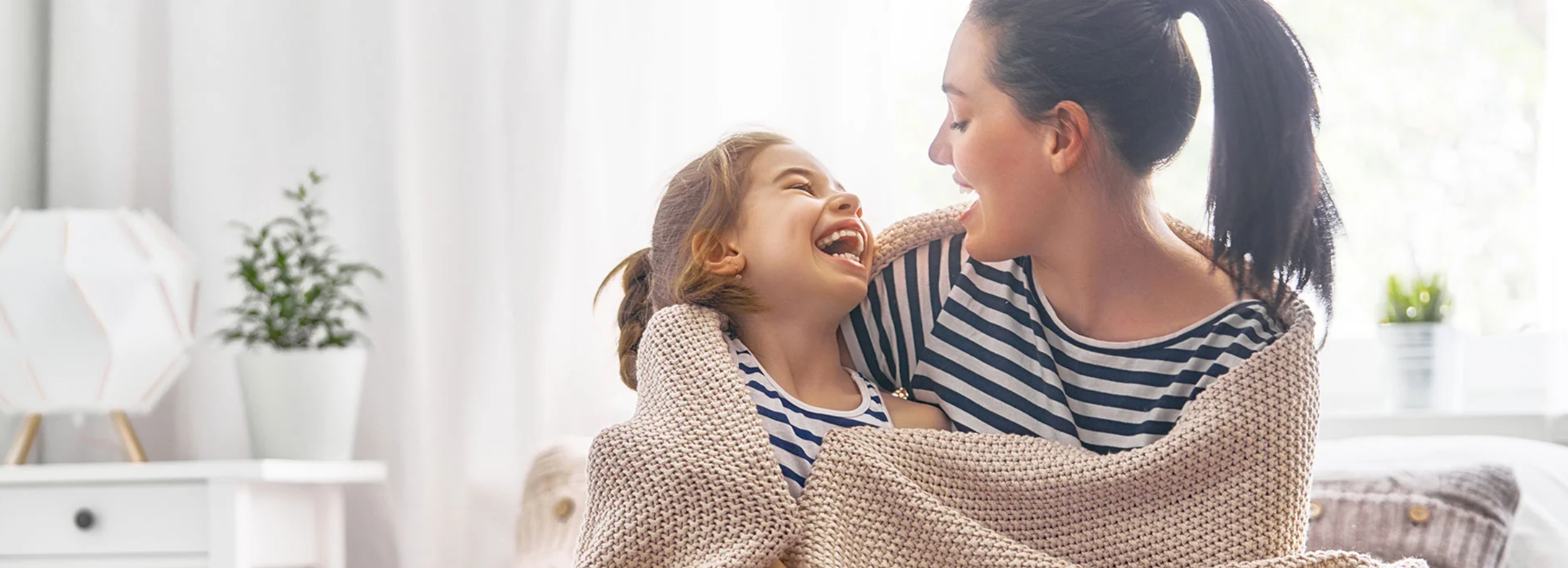 Mother and daughter wrapped in a blanket laughing.