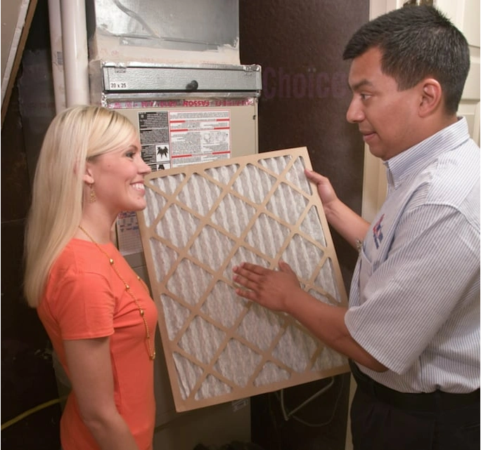 An HVAC service professional helping a woman change her furnace’s air filter during an appointment for heating repair in McKinney, TX.