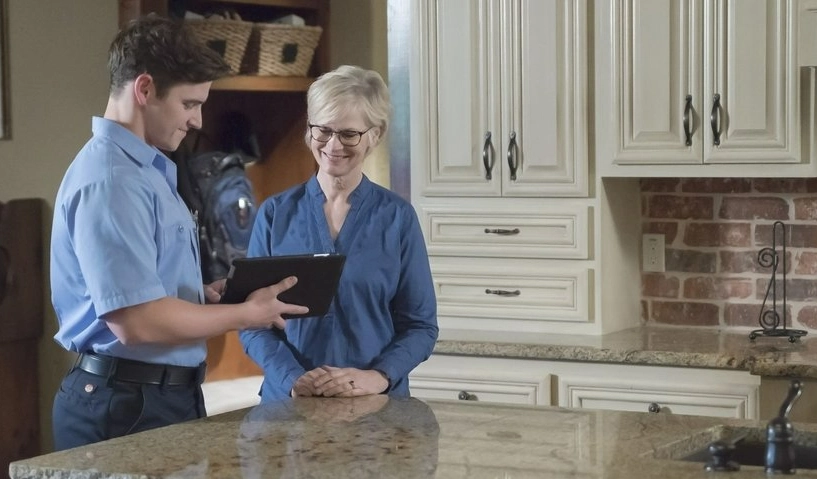 An HVAC service professional using an electronic tablet to show a woman information about heater replacement in McKinney, TX.