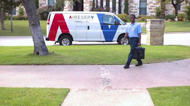 An Aire Serv van and HVAC service professional on the street in front of a home in need of furnace replacement in McKinney, TX.