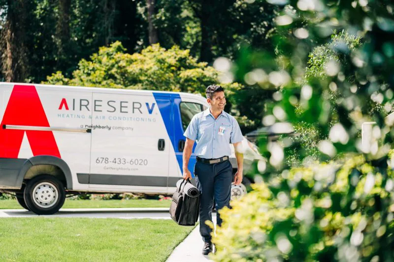 An Aire Serv technician walking to a home to perform a residential HVAC repair.