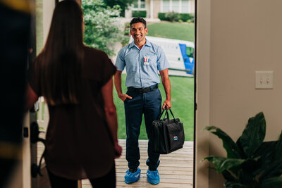 An Aire Serv emergency tech greeting his customer on her front porch