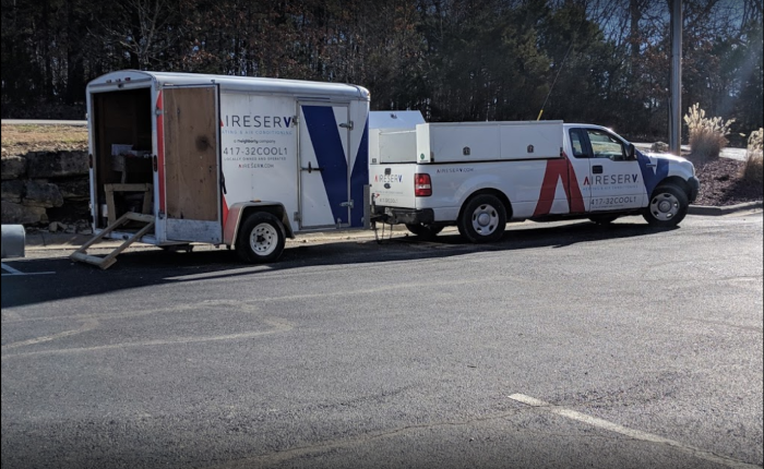 Parked Aire Serv van with tool tow in rear.