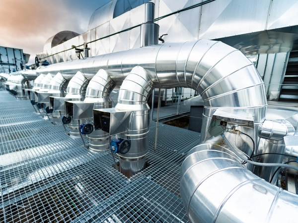 A long row of commercial air ducts and other commercial HVAC equipment on the roof of a building.