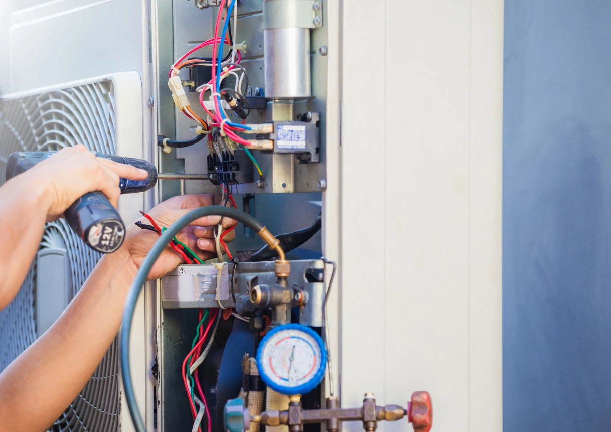 hands working on wiring in an AC unit