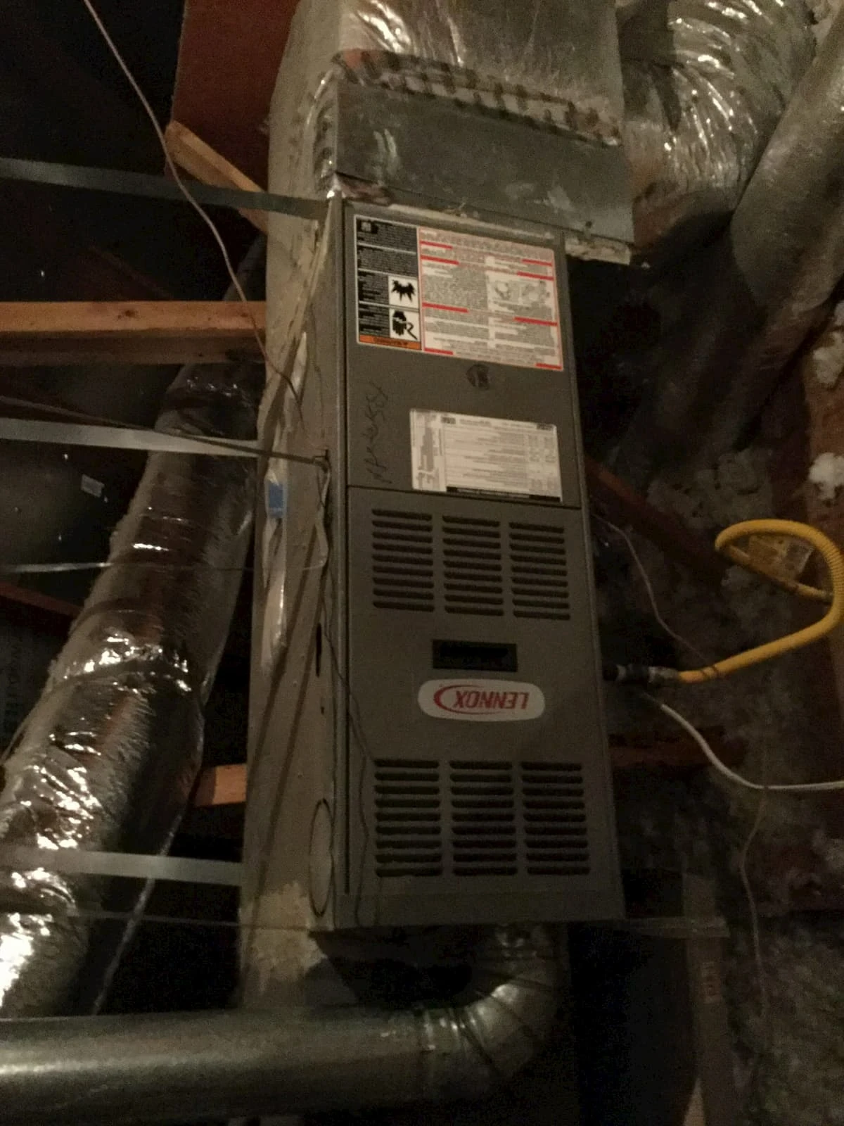 A residential furnace with attached heating vents, an exhaust vent and a fuel line after it has been serviced by Aire Serv.