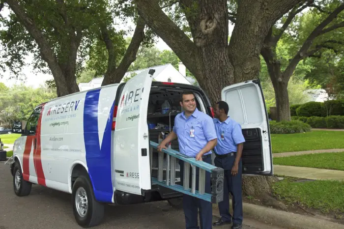 Two HVAC repair professionals from Aire Serv unloading a van and grabbing equipment used for heater repair in Dallas, TX.