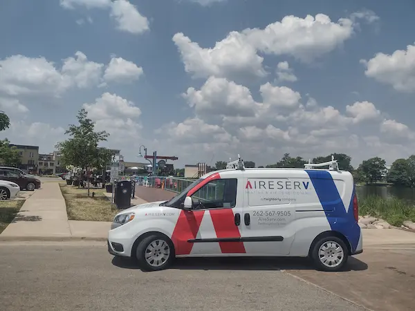 Aire Serv of Oconomowoc branded van parked in residential area.