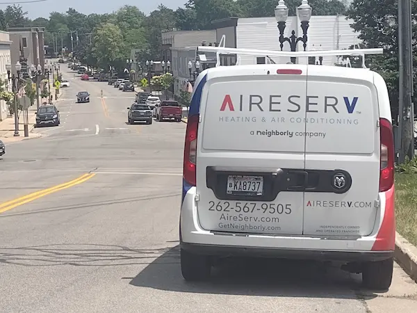 Rear of Aire Serv branded van driving down Hartland, WI street.