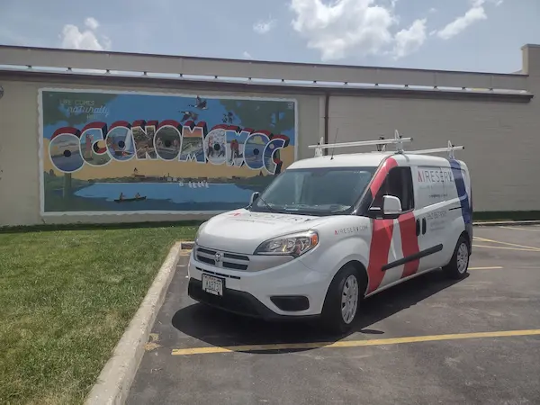 Aire Serv branded van parked in front of Oconomowoc mural.